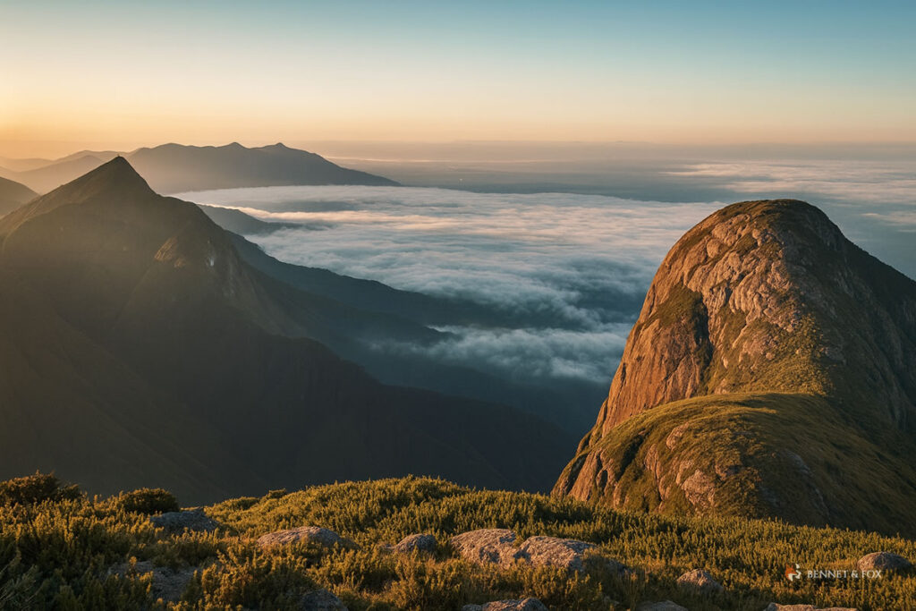 Vista panorâmica do cume do Pico Paraná ao amanhecer, com campos de altitude, rochas e mar de nuvens – cenário icônico do montanhismo e da vida outdoor no sul do Brasil