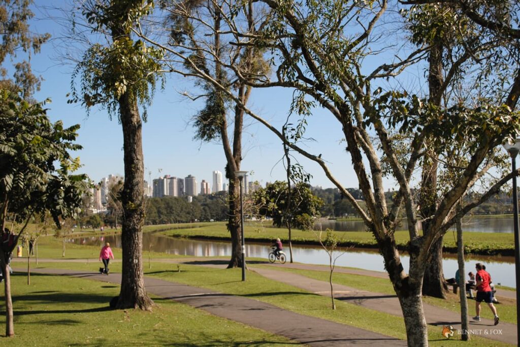 Vista do Parque Barigui em Curitiba com pessoas caminhando em trilha ao ar livre